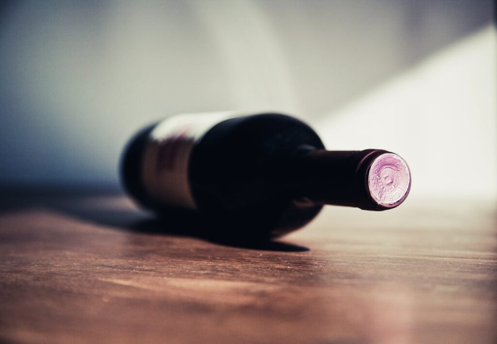 Close-up of a wine bottle on a wooden table, showcasing elegant shadows and soft lighting.