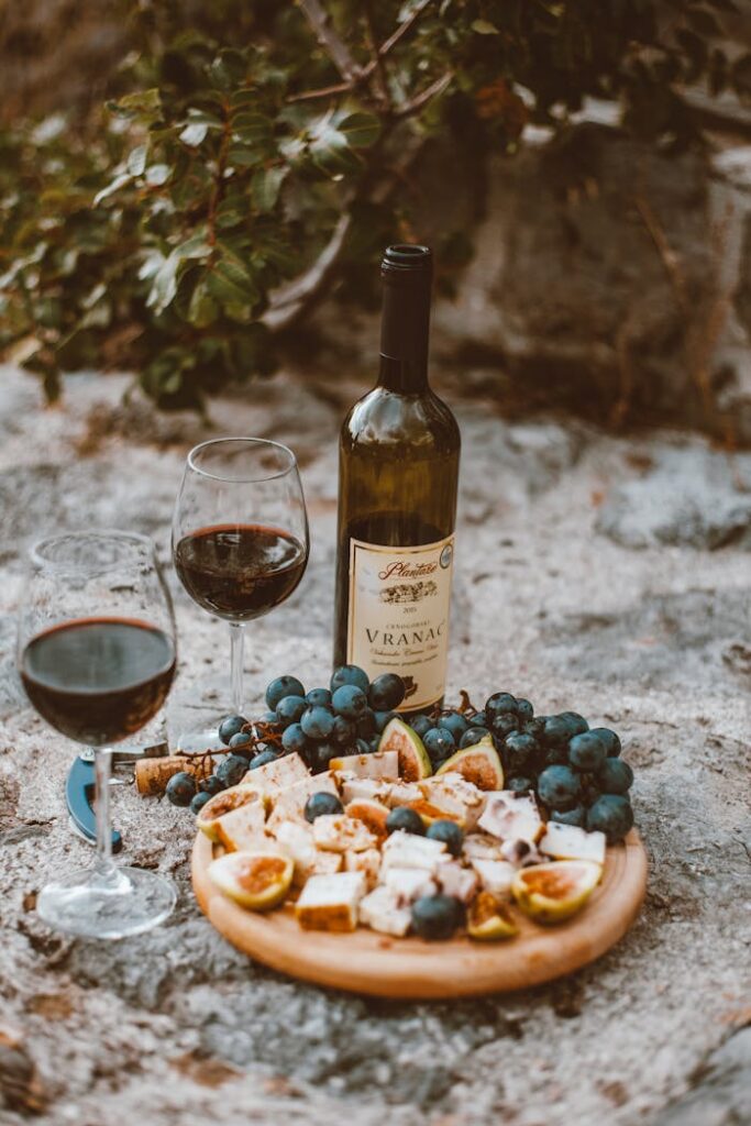 A rustic outdoor wine and cheese platter with grapes and figs, perfect for a cozy picnic.